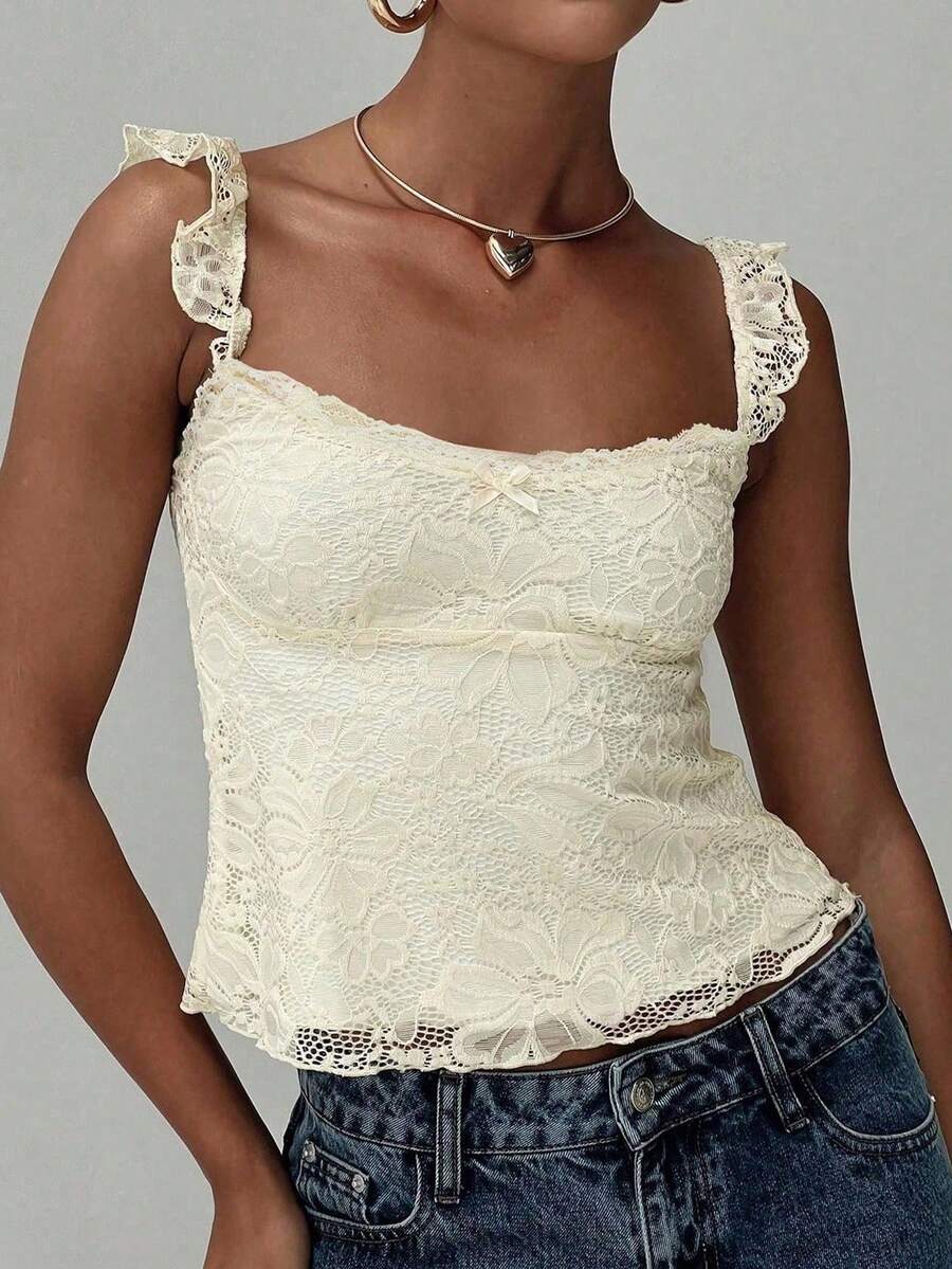 Sleeveless cami tank top featuring contrast lace patchwork design, ruffle spaghetti straps, and bow decor.