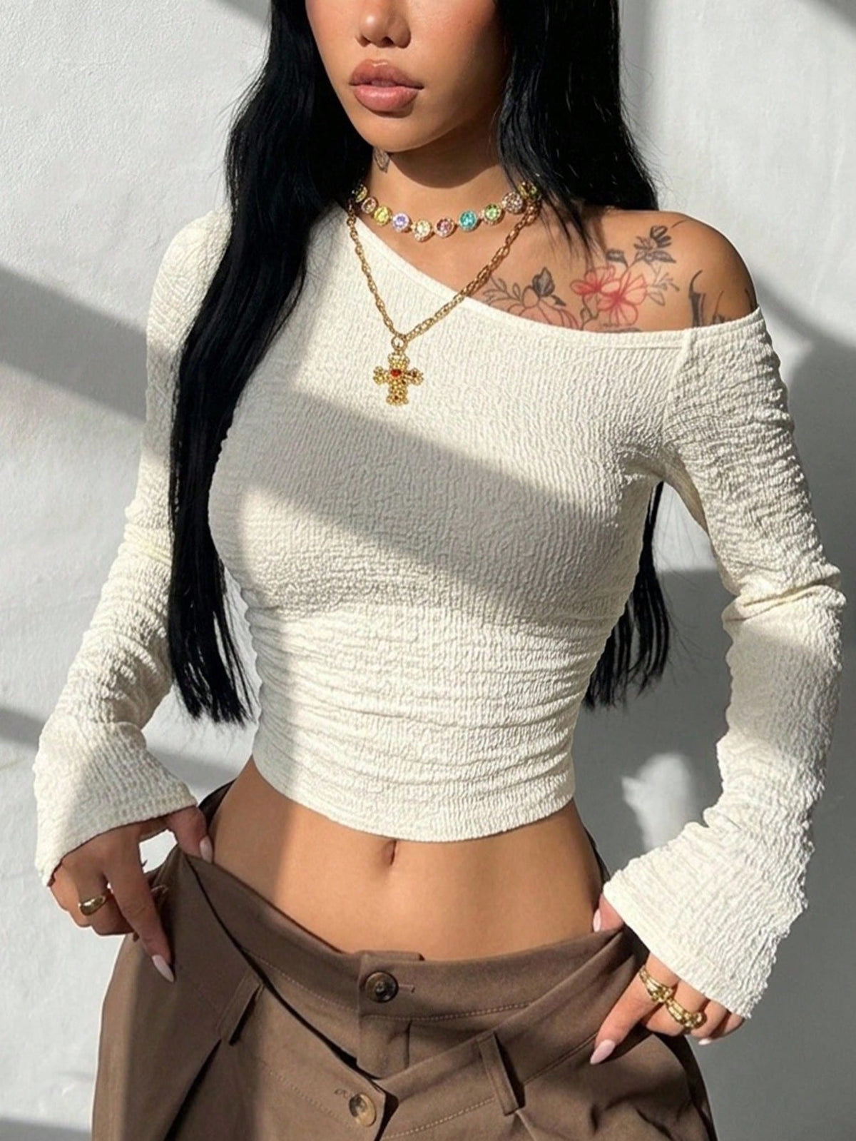 Women's slim fit long sleeve knit top featuring an asymmetrical neckline and grommet eyelet detail