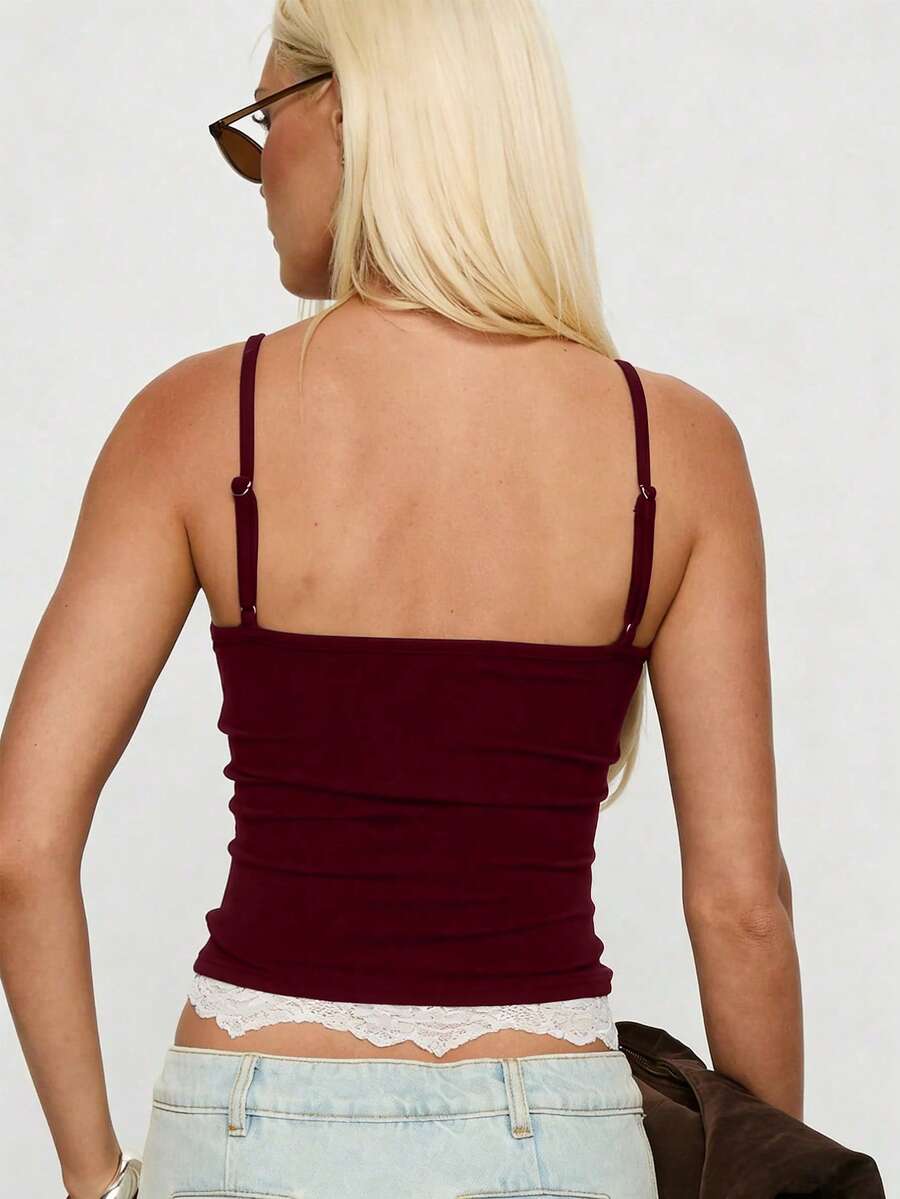 Women's black slim fit camisole top with scoop neckline, spaghetti straps, contrast lace patchwork, and appliqué details
