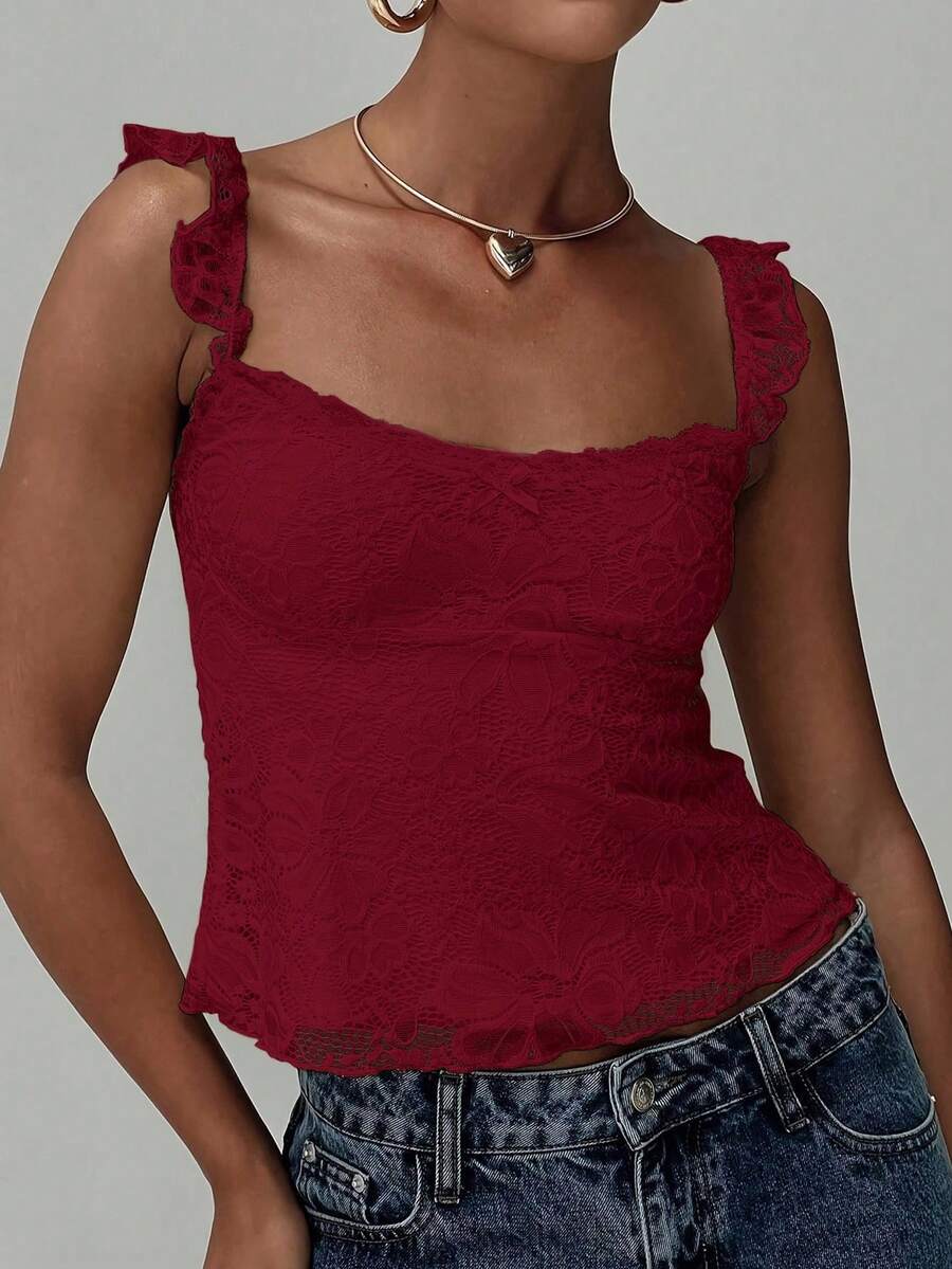 Sleeveless cami tank top featuring contrast lace patchwork design, ruffle spaghetti straps, and bow decor.