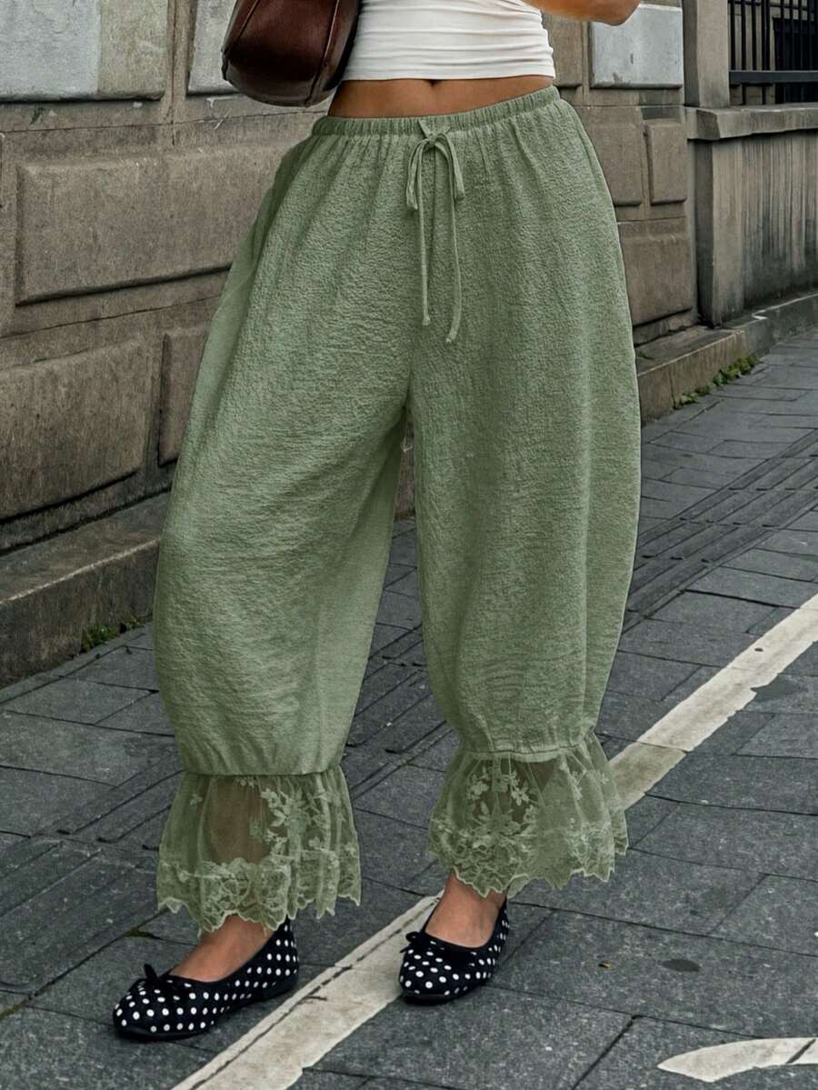 Women's loose-fitting lantern bloomer pants in capri length featuring delicate contrast lace trim and a drawstring waist.