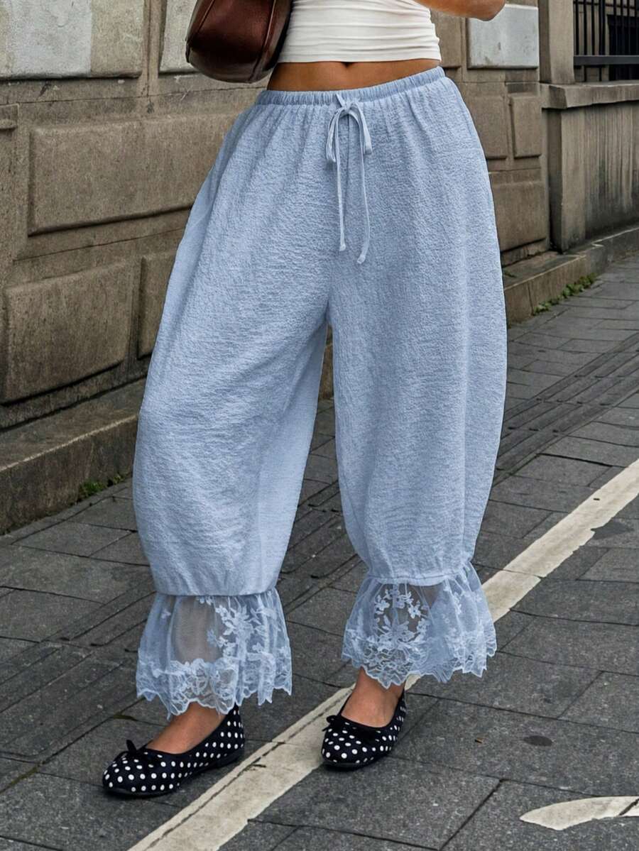 Women's loose-fitting lantern bloomer pants in capri length featuring delicate contrast lace trim and a drawstring waist.