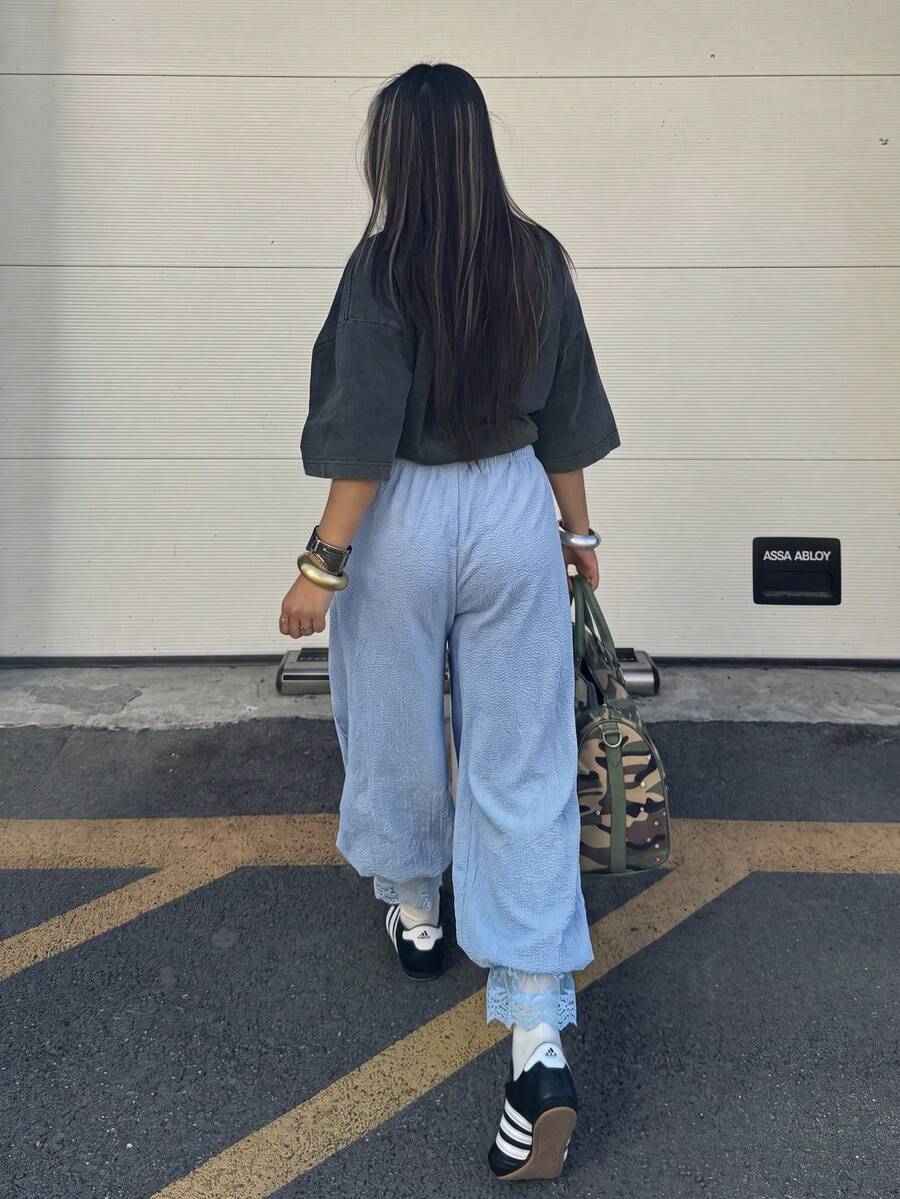 Women's loose-fitting lantern bloomer pants in capri length featuring delicate contrast lace trim and a drawstring waist.