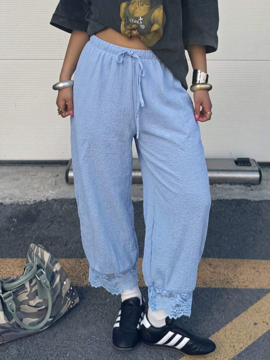 Women's loose-fitting lantern bloomer pants in capri length featuring delicate contrast lace trim and a drawstring waist.