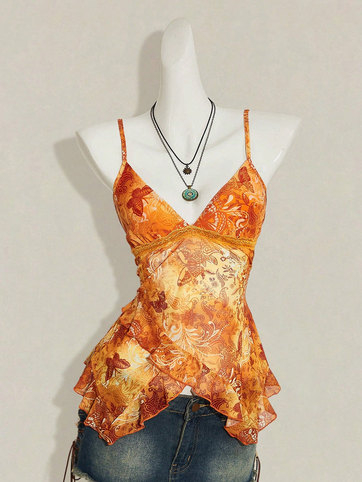 Women's graphic print camisole top featuring thin spaghetti straps, a backless cut, and an asymmetrical hem.