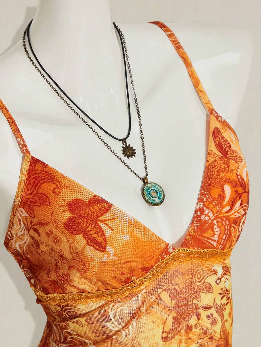 Women's graphic print camisole top featuring thin spaghetti straps, a backless cut, and an asymmetrical hem.