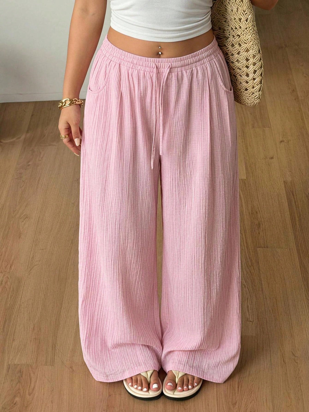Women's loose straight leg cotton pants featuring a high waist with an adjustable drawstring knot and functional side pockets.