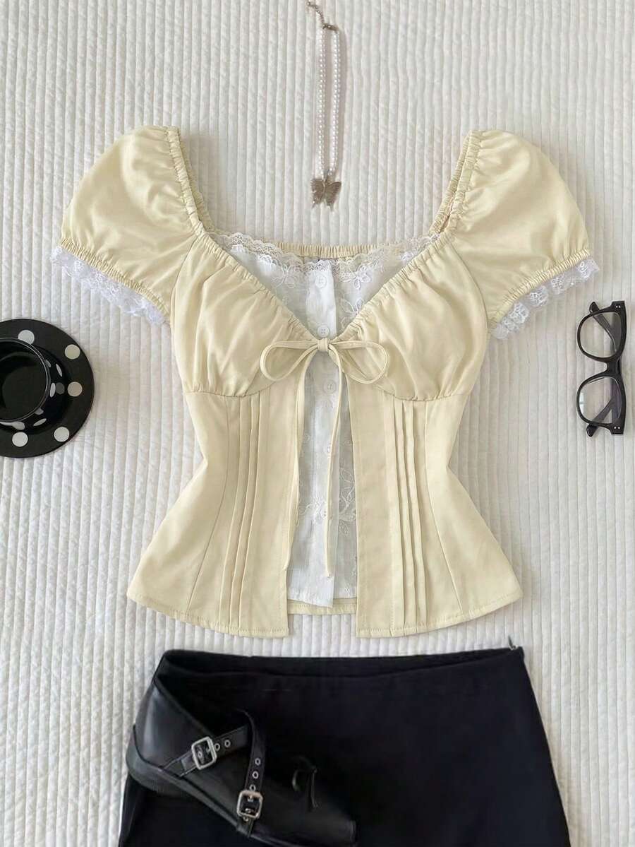Women's black 2-in-1 blouse featuring a sweetheart neckline, short puff sleeves, front tie bow accent, and asymmetrical hem.