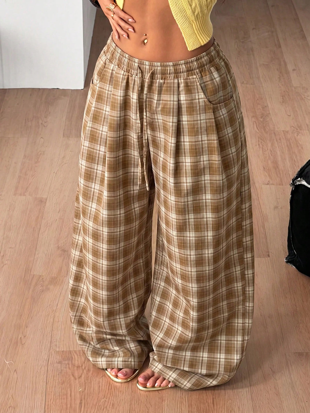 Women's loose fit brown and tan plaid wide leg pants featuring an elastic drawstring waist and side pockets.