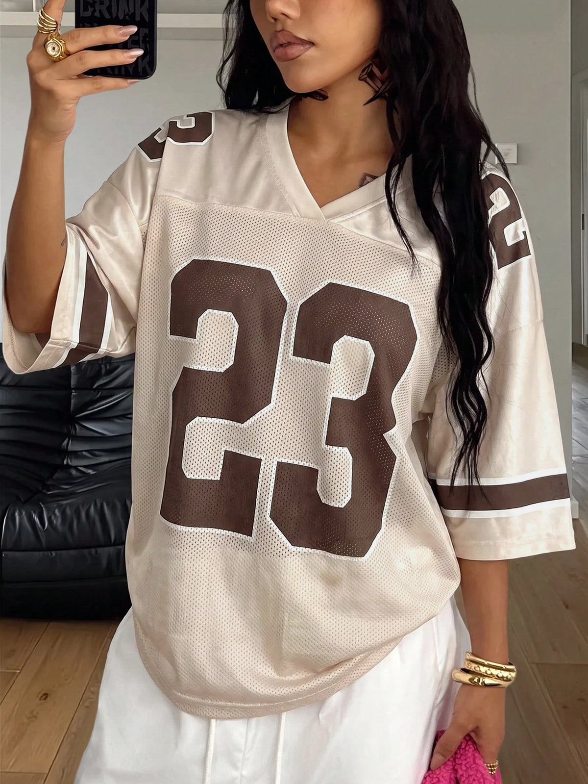 Oversized short-sleeve football jersey top featuring a V-neckline, contrast binding, and graphic number print.