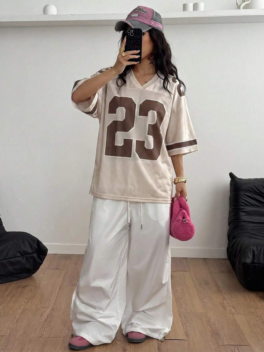 Oversized short-sleeve football jersey top featuring a V-neckline, contrast binding, and graphic number print.
