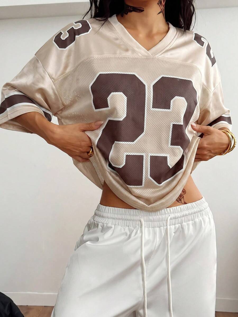 Oversized short-sleeve football jersey top featuring a V-neckline, contrast binding, and graphic number print.