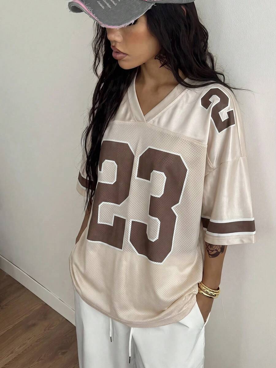 Oversized short-sleeve football jersey top featuring a V-neckline, contrast binding, and graphic number print.