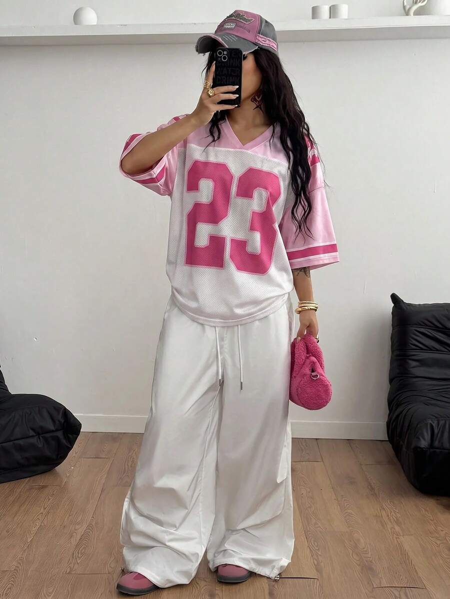 Oversized short-sleeve football jersey top featuring a V-neckline, contrast binding, and graphic number print.