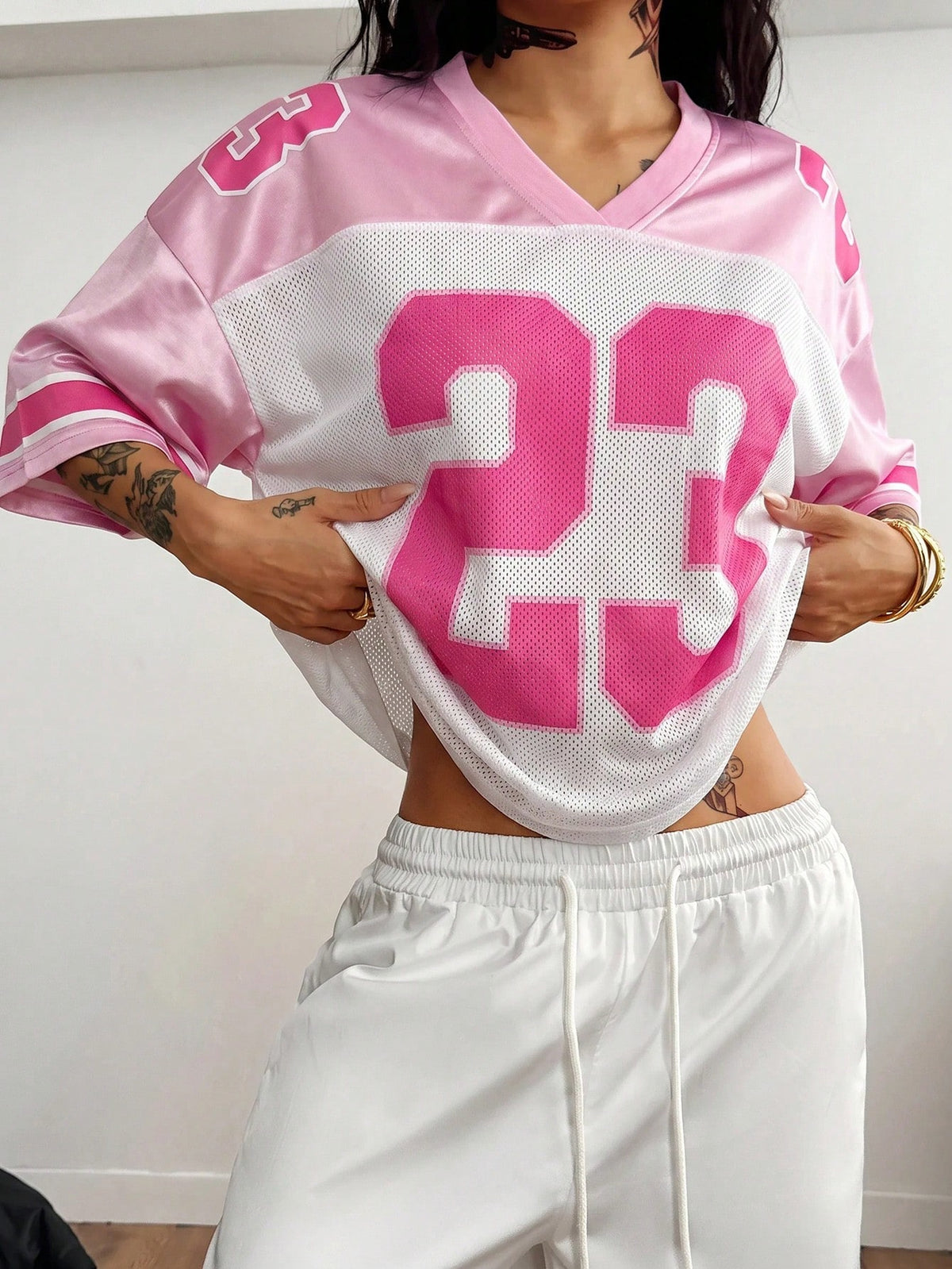 Oversized short-sleeve football jersey top featuring a V-neckline, contrast binding, and graphic number print.