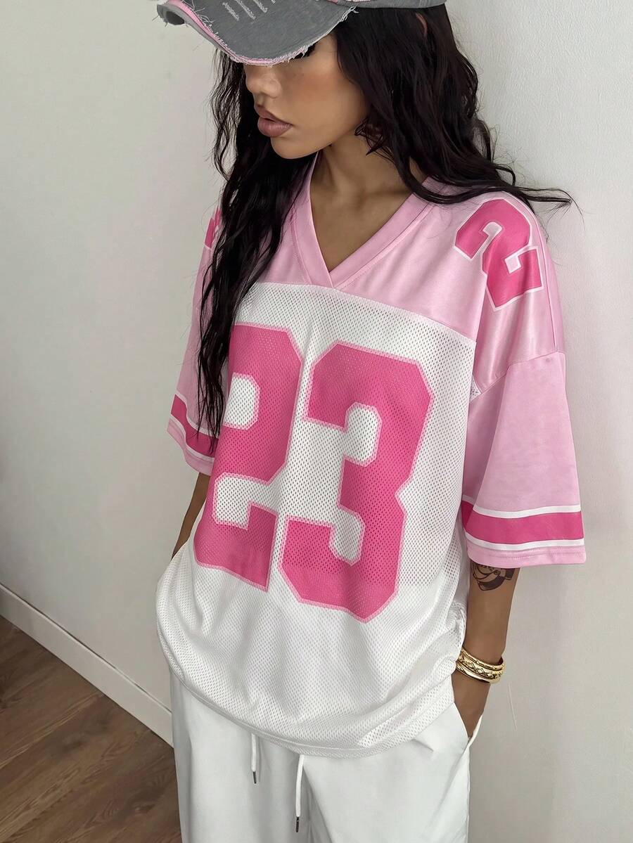 Oversized short-sleeve football jersey top featuring a V-neckline, contrast binding, and graphic number print.