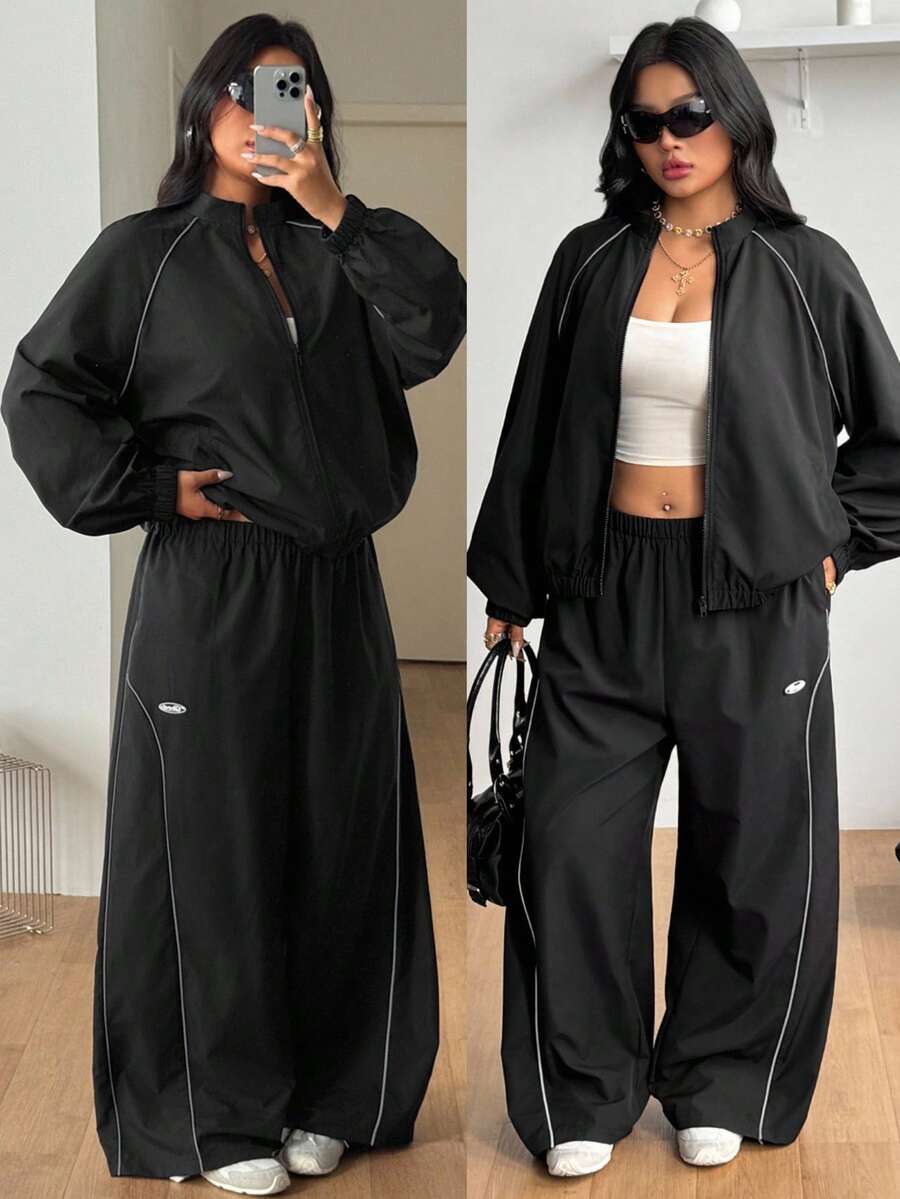 Women's plus size two-piece casual tracksuit set in black, featuring a loose-fit zip-up jacket with stand collar and matching cropped parachute pants.
