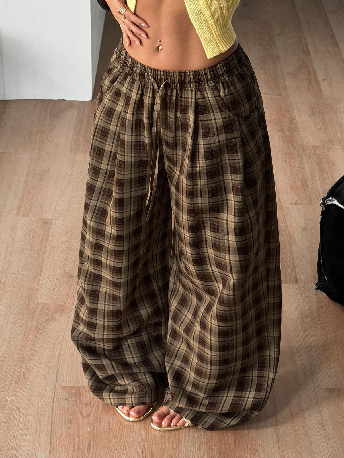 Women's loose fit brown and tan plaid wide leg pants featuring an elastic drawstring waist and side pockets.