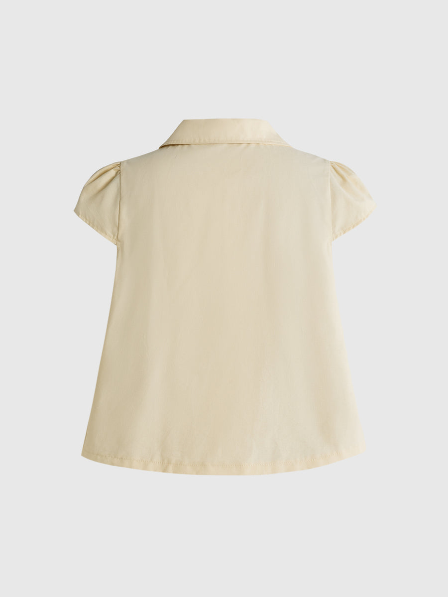 Women's short puff sleeve cotton blouse featuring a Peter Pan collar, double button detail, and front pocket.