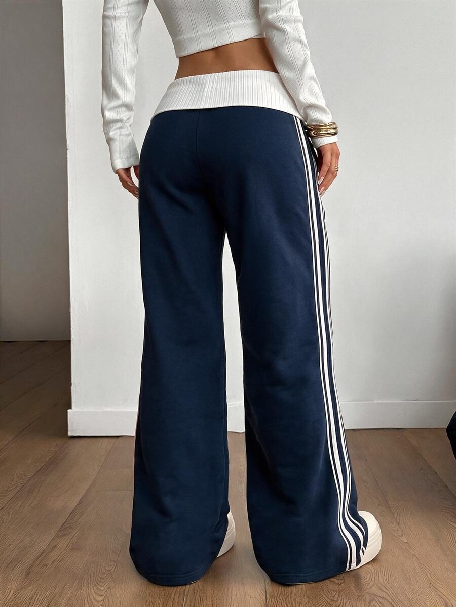 Women's wide leg flare sweatpants featuring a black and white colorblock contrast fold waistband and side stripe details.