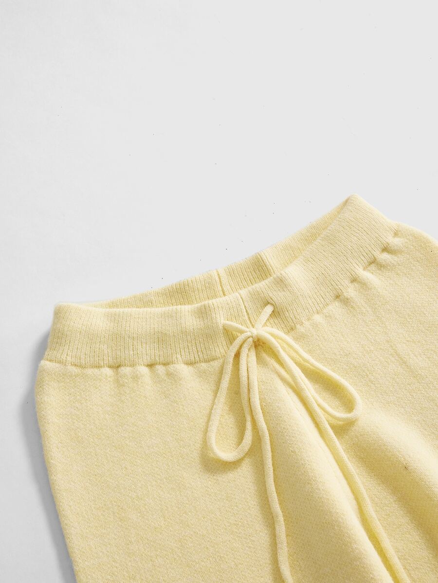 Women's two-piece rib-knit sweater set featuring a long-sleeve cold-shoulder crop top with strap details and matching wide-leg pants.