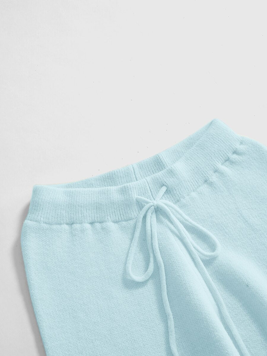 Women's two-piece rib-knit sweater set featuring a long-sleeve cold-shoulder crop top with strap details and matching wide-leg pants.