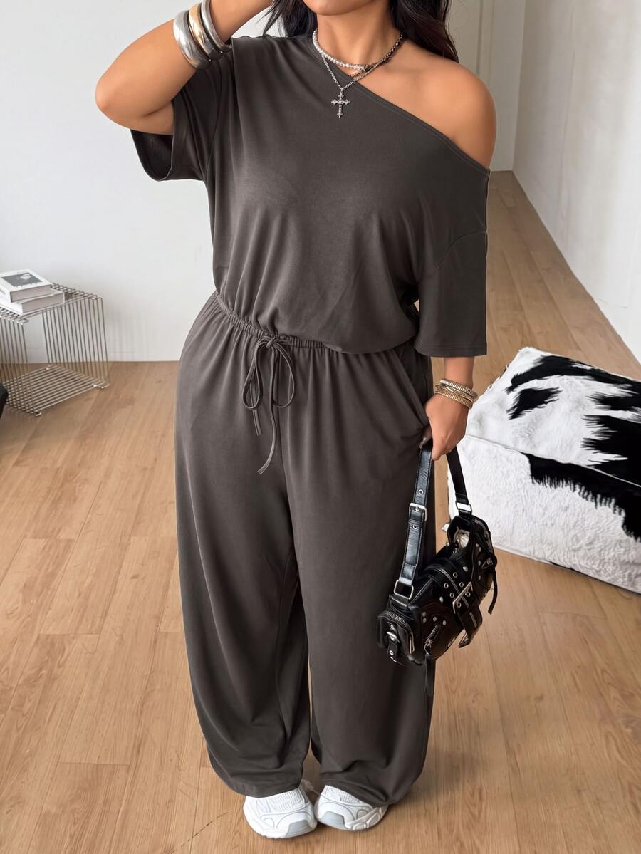 Plus size women's wide leg jumpsuit in dark grey featuring an asymmetrical neckline, short batwing sleeves, and a drawstring high waist with side pockets.