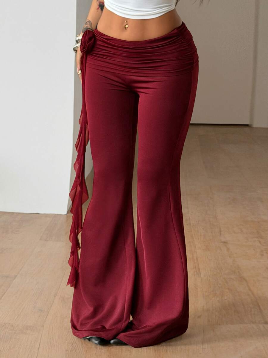 Black low waist flare pants featuring 3D rose and side stripe detailing in stretchy mesh fabric.