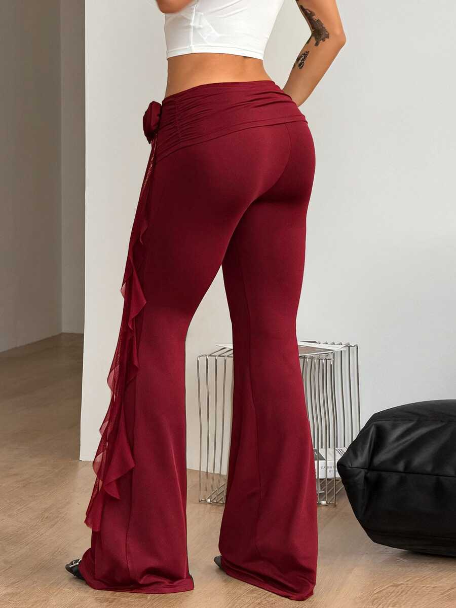 Black low waist flare pants featuring 3D rose and side stripe detailing in stretchy mesh fabric.