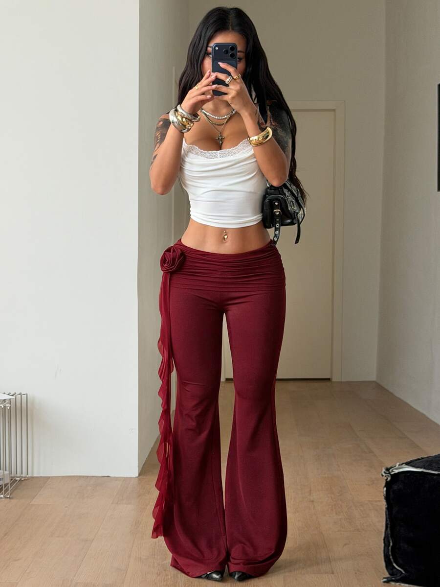 Black low waist flare pants featuring 3D rose and side stripe detailing in stretchy mesh fabric.