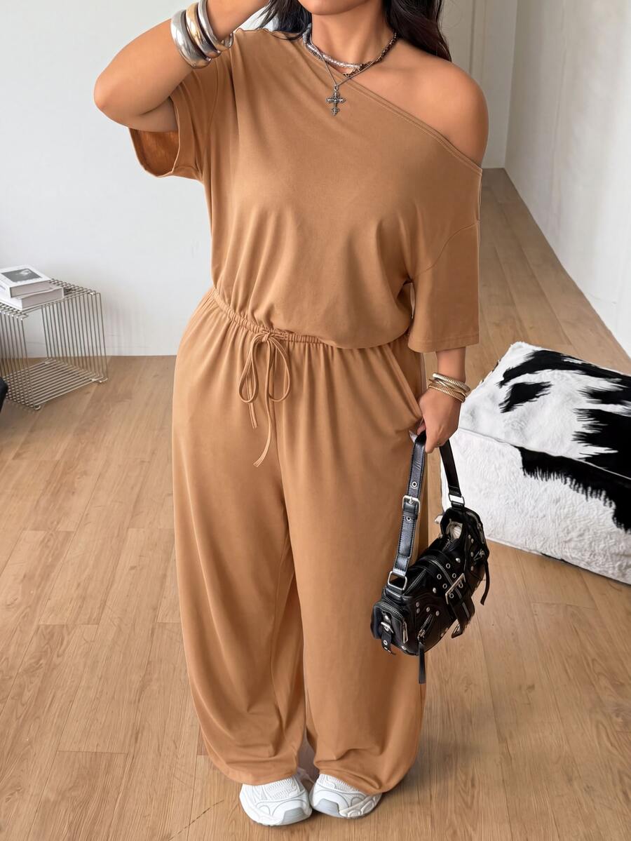 Plus size women's wide leg jumpsuit in dark grey featuring an asymmetrical neckline, short batwing sleeves, and a drawstring high waist with side pockets.