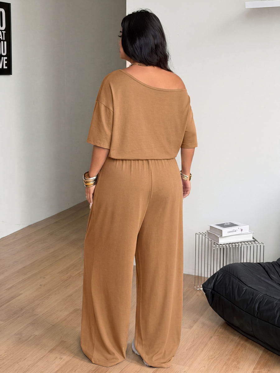 Plus size women's wide leg jumpsuit in dark grey featuring an asymmetrical neckline, short batwing sleeves, and a drawstring high waist with side pockets.