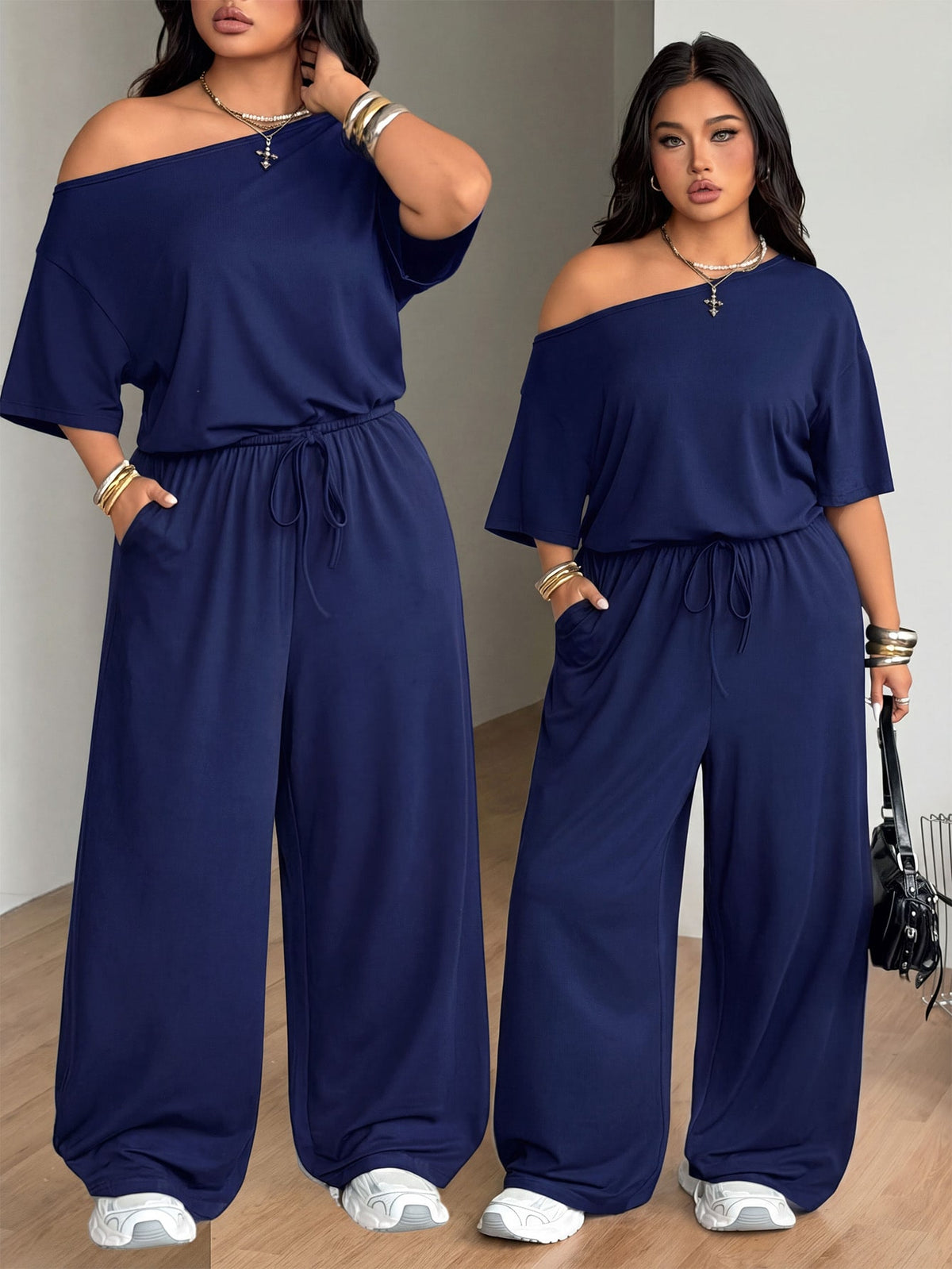 Plus size women's wide leg jumpsuit in dark grey featuring an asymmetrical neckline, short batwing sleeves, and a drawstring high waist with side pockets.