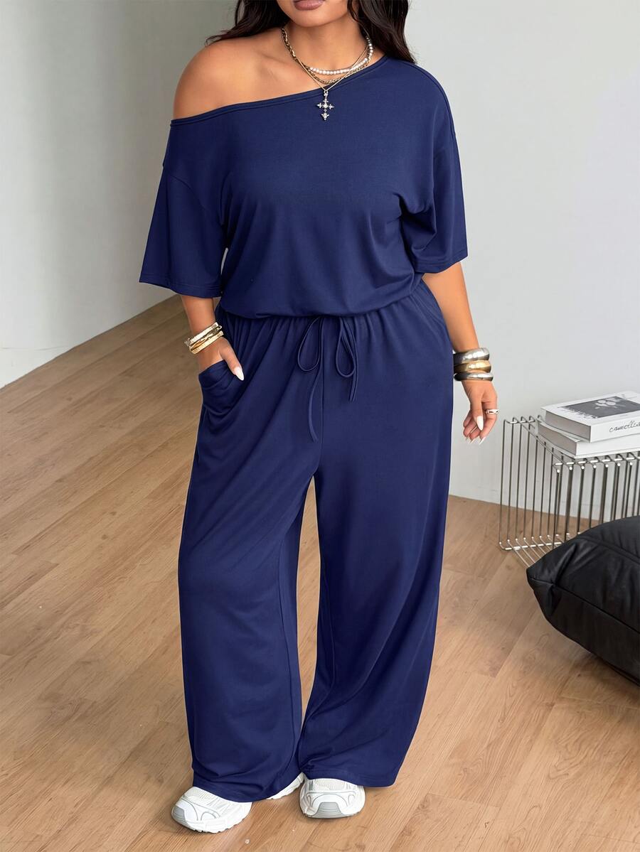 Plus size women's wide leg jumpsuit in dark grey featuring an asymmetrical neckline, short batwing sleeves, and a drawstring high waist with side pockets.