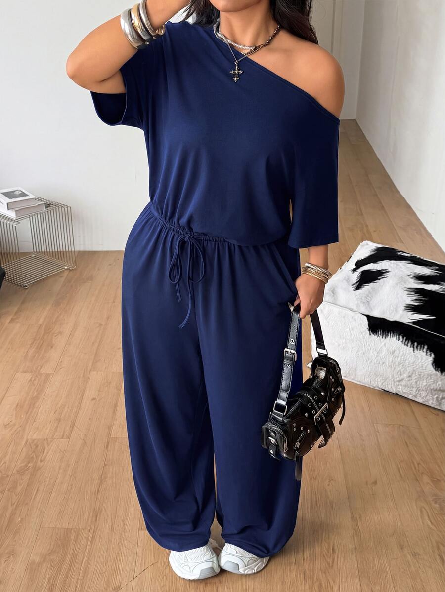Plus size women's wide leg jumpsuit in dark grey featuring an asymmetrical neckline, short batwing sleeves, and a drawstring high waist with side pockets.