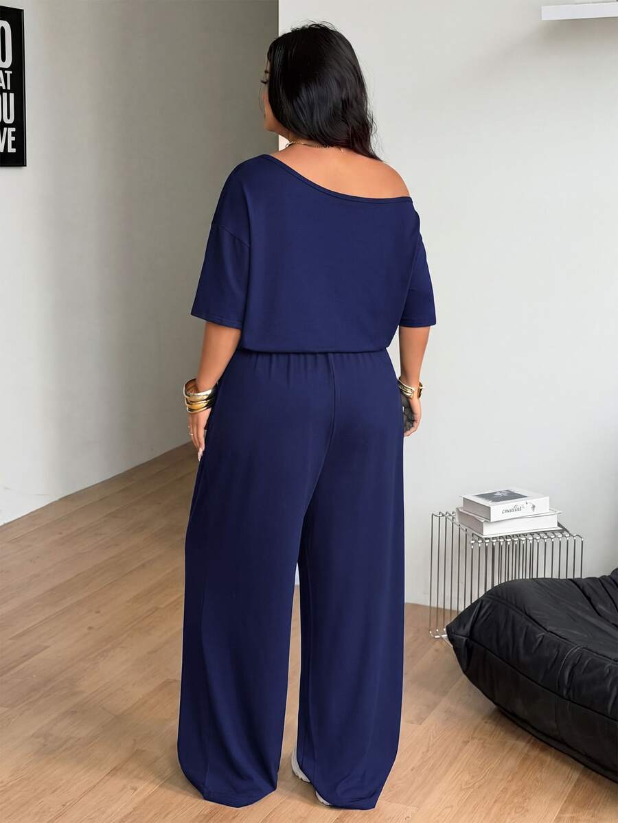 Plus size women's wide leg jumpsuit in dark grey featuring an asymmetrical neckline, short batwing sleeves, and a drawstring high waist with side pockets.