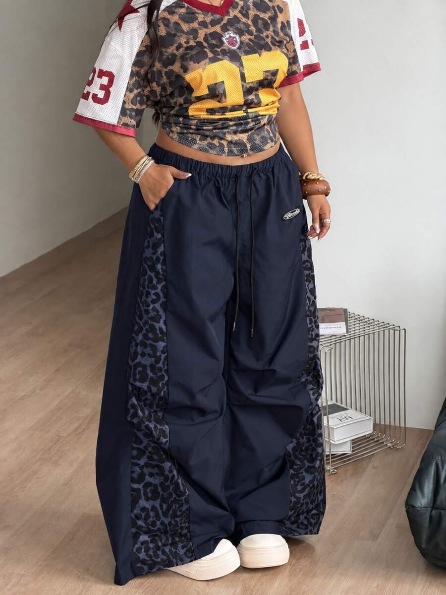 Women's high waist wide leg pants in black featuring leopard print patchwork details and an elastic drawstring waistband.