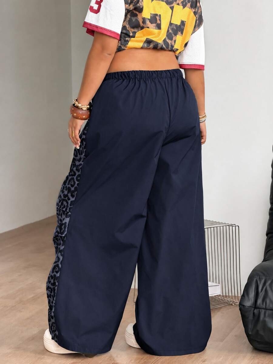Women's high waist wide leg pants in black featuring leopard print patchwork details and an elastic drawstring waistband.
