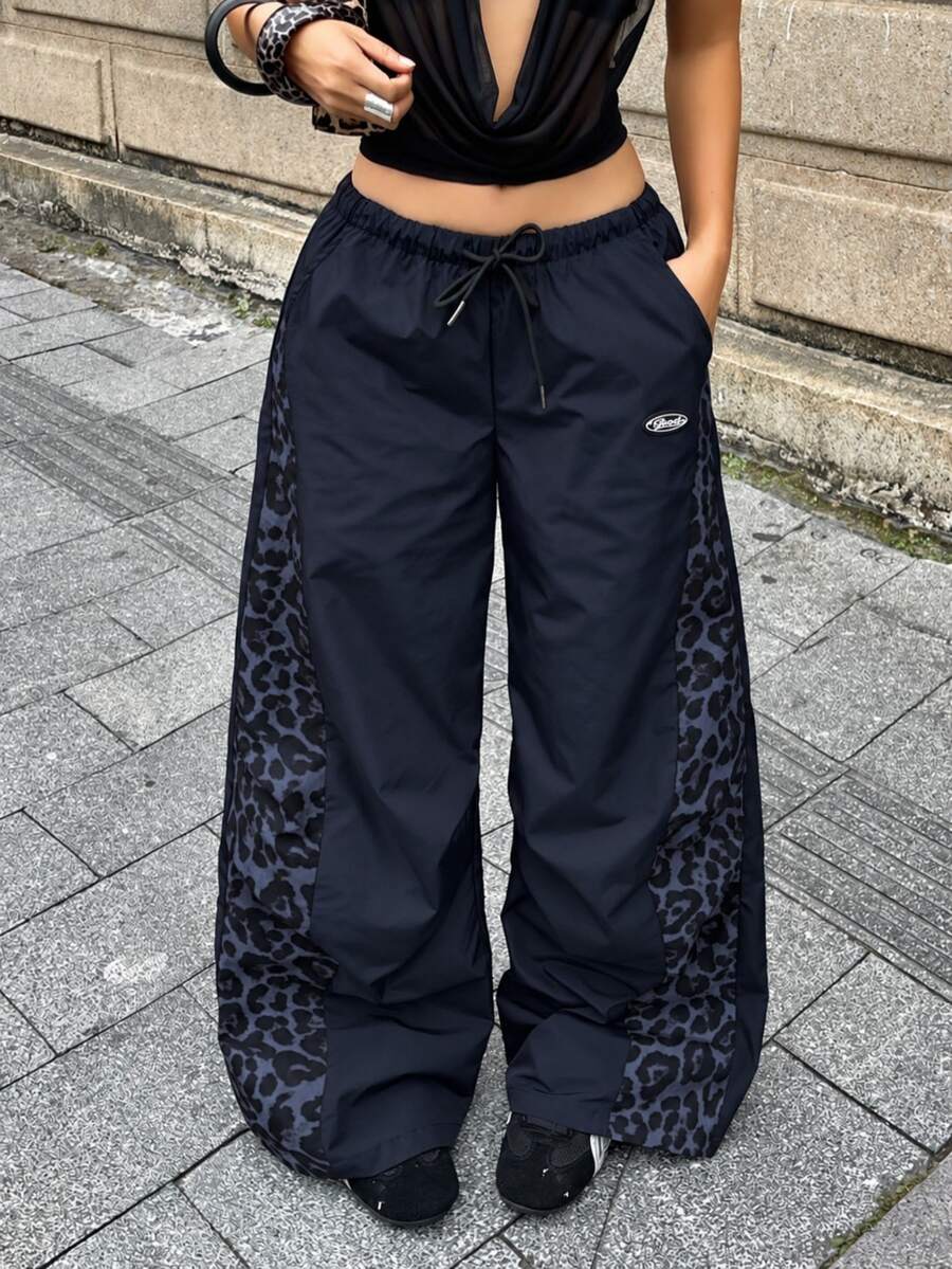 Women's high waist wide leg pants in black featuring leopard print patchwork details and an elastic drawstring waistband.