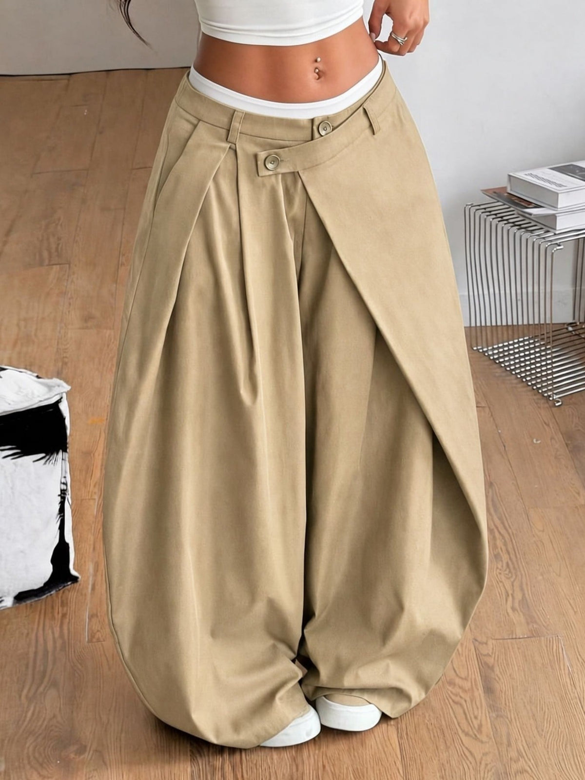 Front view of women's loose curved banana pants featuring a mid waist, side pockets, and asymmetrical plicated hem.