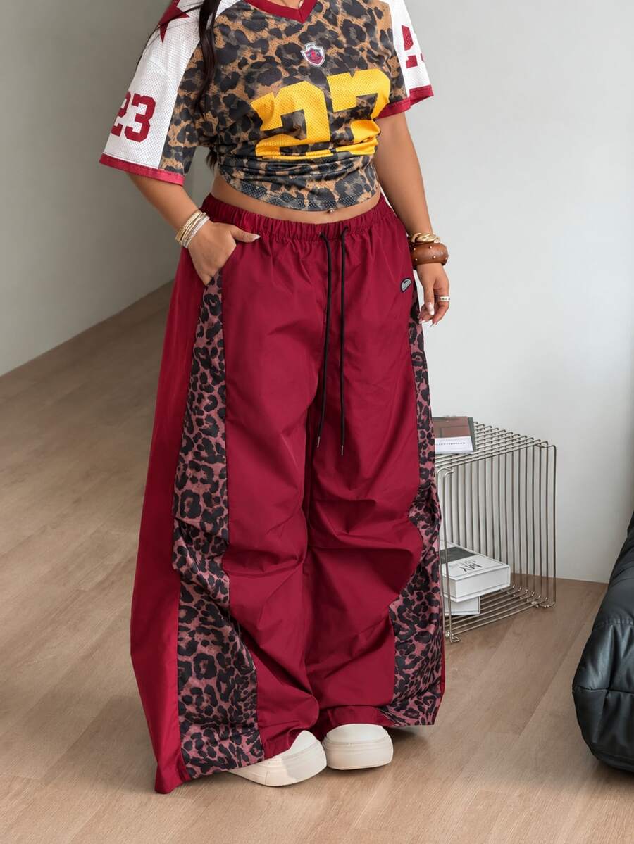 Women's high waist wide leg pants in black featuring leopard print patchwork details and an elastic drawstring waistband.