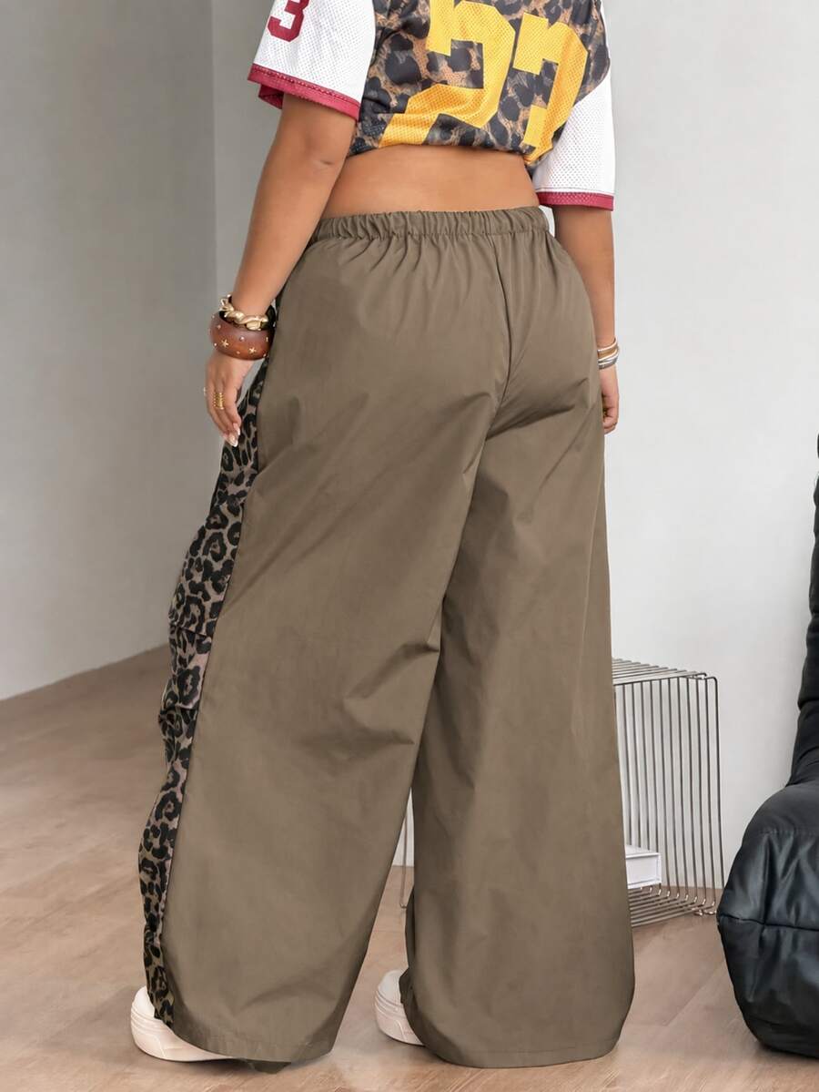 Women's high waist wide leg pants in black featuring leopard print patchwork details and an elastic drawstring waistband.