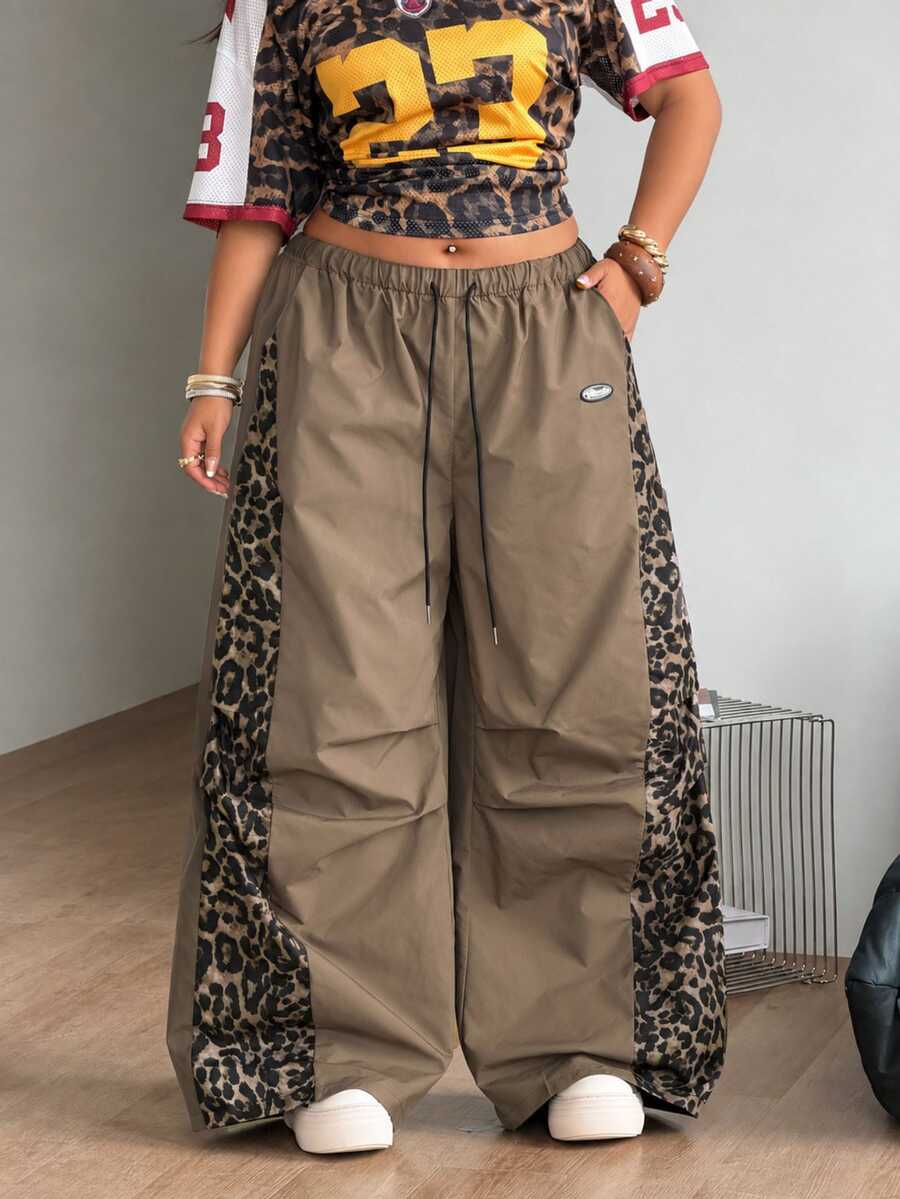 Women's high waist wide leg pants in black featuring leopard print patchwork details and an elastic drawstring waistband.