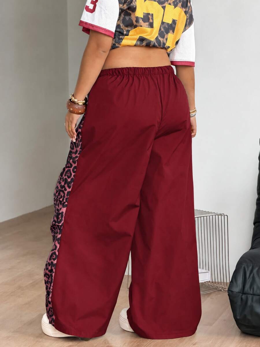 Women's high waist wide leg pants in black featuring leopard print patchwork details and an elastic drawstring waistband.