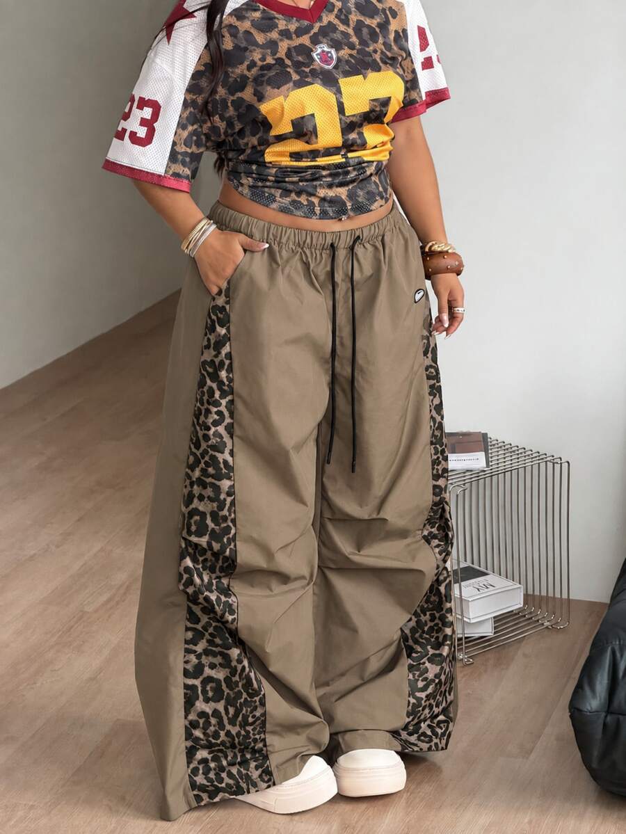 Women's high waist wide leg pants in black featuring leopard print patchwork details and an elastic drawstring waistband.