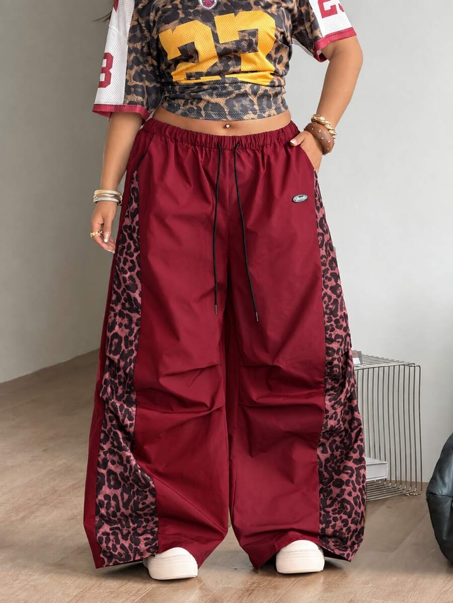 Women's high waist wide leg pants in black featuring leopard print patchwork details and an elastic drawstring waistband.