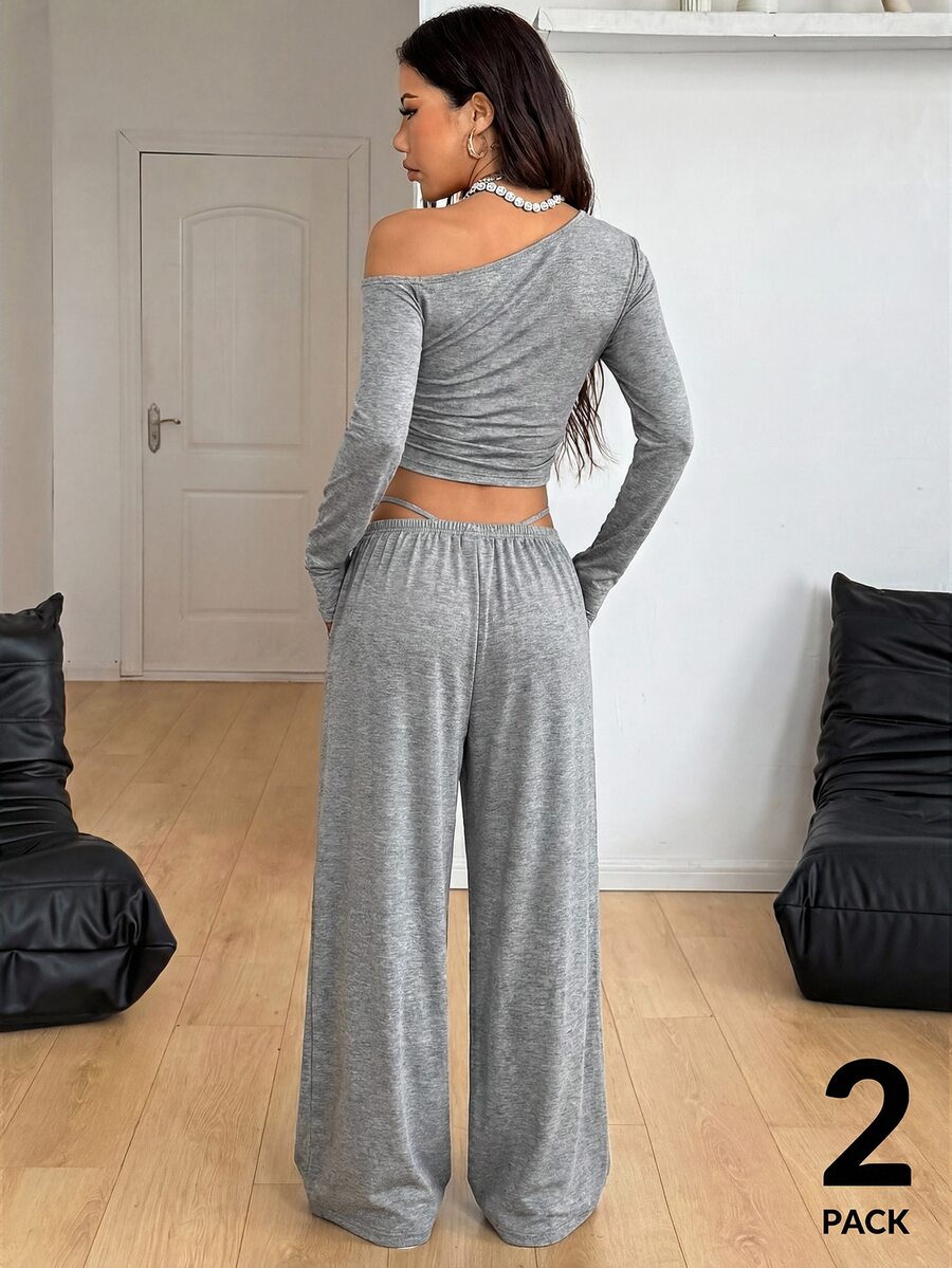 Women's two-piece knit lounge set featuring a black long sleeve asymmetrical crop top and matching high-waisted wide leg sweatpants.