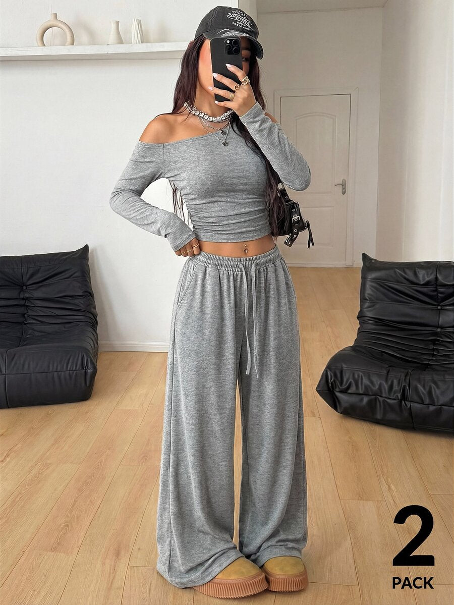 Women's two-piece knit lounge set featuring a black long sleeve asymmetrical crop top and matching high-waisted wide leg sweatpants.