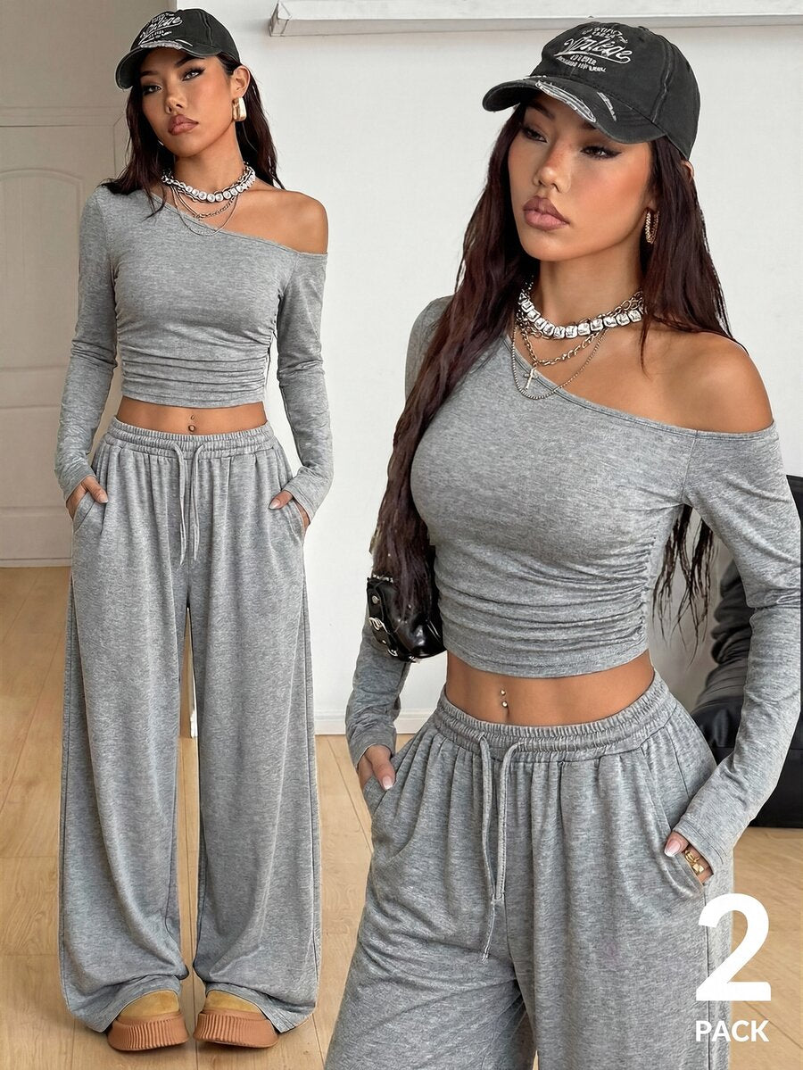 Women's two-piece knit lounge set featuring a black long sleeve asymmetrical crop top and matching high-waisted wide leg sweatpants.