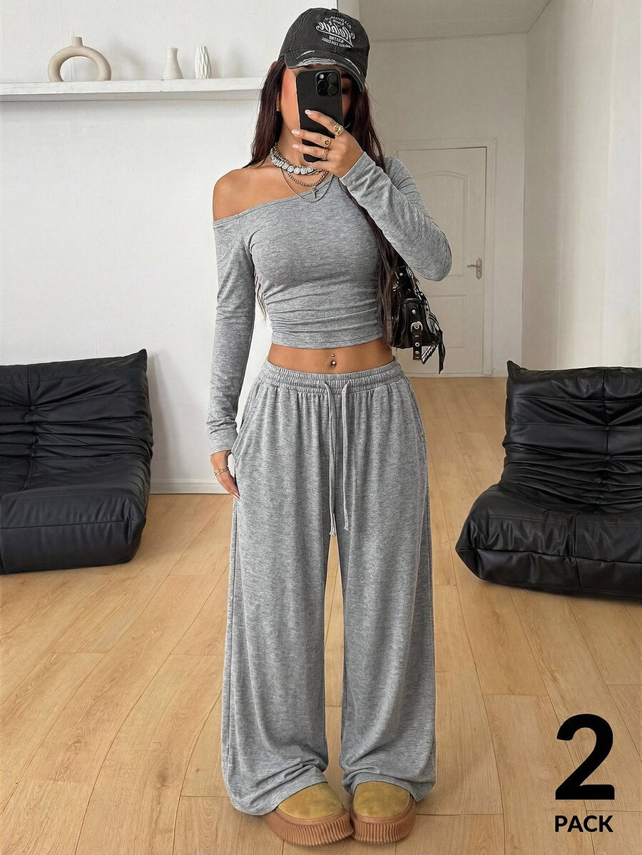 Women's two-piece knit lounge set featuring a black long sleeve asymmetrical crop top and matching high-waisted wide leg sweatpants.